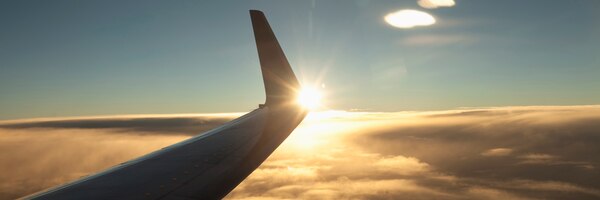 Airplane wing above clouds at sunset